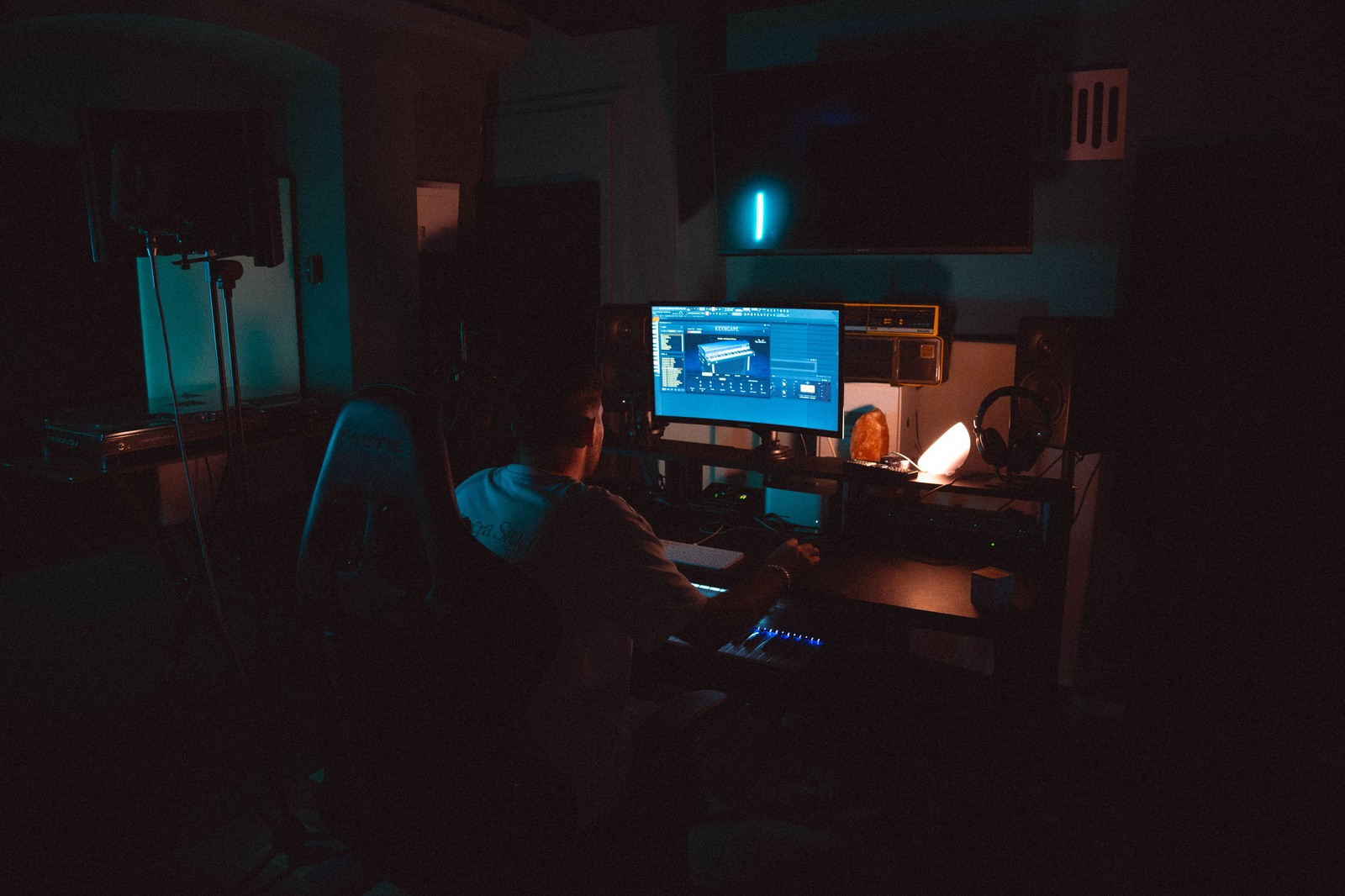 La sala di regia di Hypeless Studio in penombra, vista da dietro la postazione di lavoro